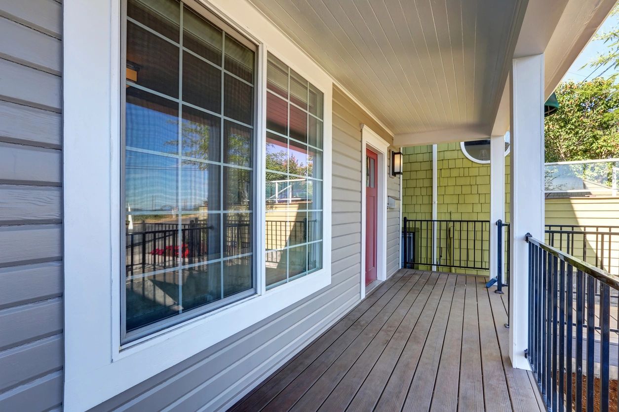 Covered front porch of a home with siding, windows, and a railing.